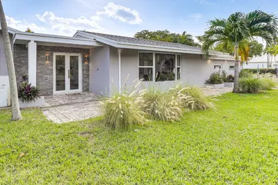 a white house with palm trees in a yard at Relax in the Sun! Gem 1 Mi to Las Olas Beach in Fort Lauderdale