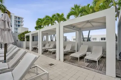 a patio with white chairs and umbrellas and palm trees at 2BR W Residence 18th Floor, Ocean, Inter-coastal, & City Views in Fort Lauderdale