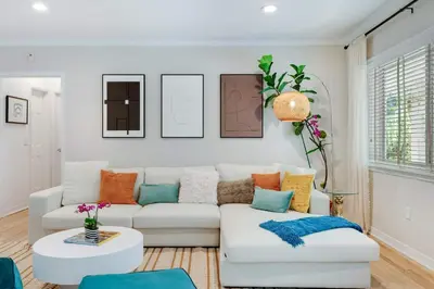 a living room with a white couch with colorful pillows at Garden Grove- Miami Home with Private Pool in Miami
