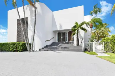 a white house with palm trees and a driveway at Villa Moonlight Haven in Miami Beach