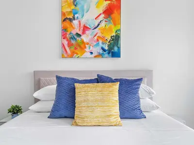 a bed with blue and white pillows and a painting at X Lounge VII-Private Sky Residence in Miami