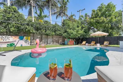 a swimming pool with two drinks and a pink flamingo at 5BR Villa with Heated Pool, Firepit and 10mins to Beach in Highland Lakes