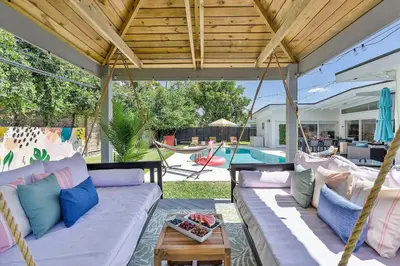 a porch with a white couch and a swing at 5BR Villa with Heated Pool, Firepit and 10mins to Beach in Highland Lakes