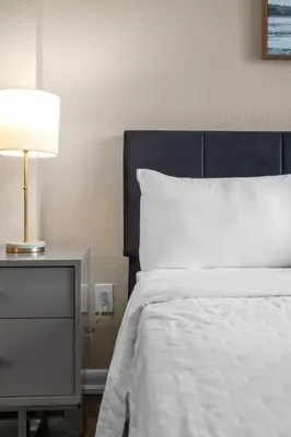a bedroom with a bed and a lamp on a nightstand at Centrally Located 2 BED in the Heart of NMB in North Miami