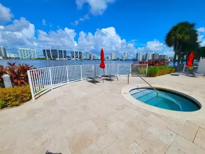 a patio with a pool with a fence and a table and chairs at Stylish, classy Bayfront view apt, Walk to beach in Sunny Isles Beach
