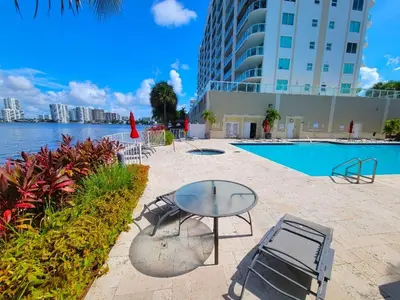 a glass table and chairs next to a swimming pool at Stylish, classy Bayfront view apt, Walk to beach in Sunny Isles Beach