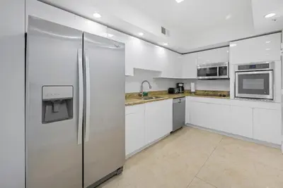 a kitchen with white cabinets and a stainless steel refrigerator at Oceanfront corner unit in Hollywood