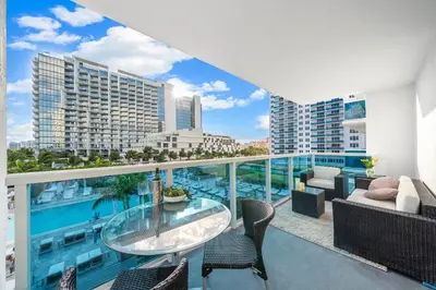 an apartment balcony with a glass table and chairs at Roney Palace 408 in Miami Beach