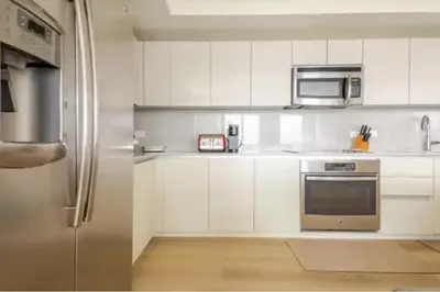 a kitchen with white cabinets and a stainless steel refrigerator at Beachwalk Resort in Hallandale Beach