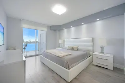 a white bedroom with a bed and a large window at Golden Bay 702 in Sunny Isles Beach