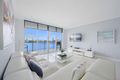 a living room with white furniture and a large window at Golden Bay 702 in Sunny Isles Beach