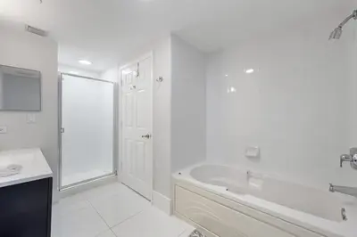 a white bathroom with a tub and a sink at Golden Bay 702 in Sunny Isles Beach