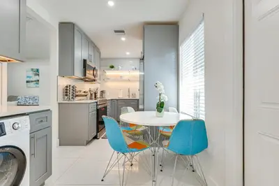 a kitchen with a white table and blue chairs at 1 Mi to Las Olas Eats! Modern Apt with Shared Patio in Fort Lauderdale
