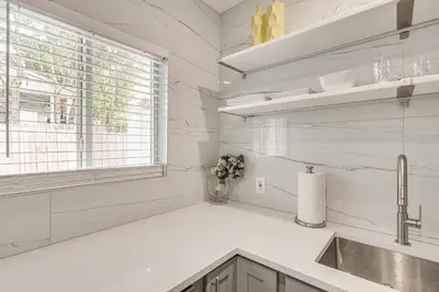 a white kitchen with a sink and a window at Walk to Dining and Nightlife! Chic Apt Near Las Olas in Fort Lauderdale