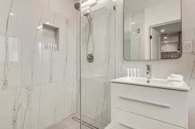 a white bathroom with a shower and a sink at Walk to Dining and Nightlife! Chic Apt Near Las Olas in Fort Lauderdale