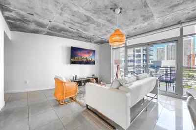 a living room with a white couch and a large window at Contemporary Midtown Condo - Pool & Free Parking in Miami