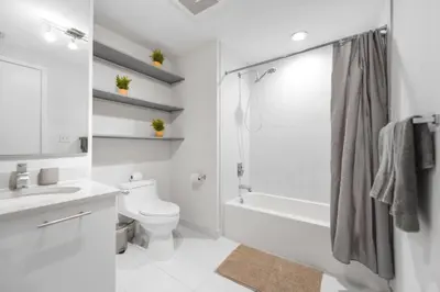 a white bathroom with a shower and a toilet at Contemporary Midtown Condo - Pool & Free Parking in Miami