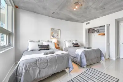 two beds in a room with white walls at Contemporary Midtown Condo - Pool & Free Parking in Miami