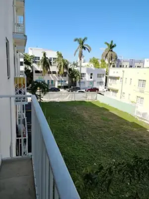 a balcony with a yard with palm trees and buildings at The Blue Breeze - Parking included in Miami Beach