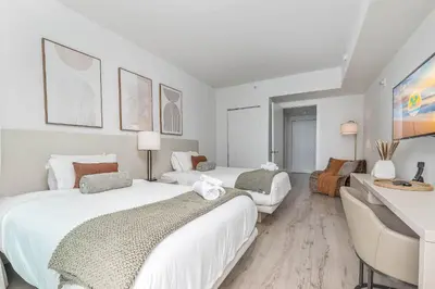 a white bedroom with two beds and a desk at Luxurious Beachfront 2-Bedroom 2-Bathroom with balcony Condo at Lyft Resort & Residences - Miami Beach in Hollywood
