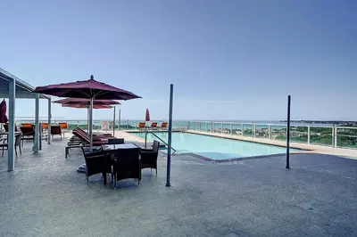 a pool with a table and chairs and an umbrella at Coconut Grove Bayview Retreat 2 King Suites Pool Gym and Free Parking in Miami