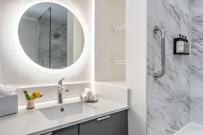 a white bathroom with a sink and a mirror at Elevated Grove Escape with Balcony & Bay Views-Includes Parking in Miami