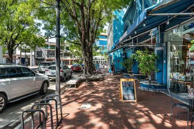 a city street with parked cars and a sign on the sidewalk at Elevated Grove Escape with Balcony & Bay Views-Includes Parking in Miami