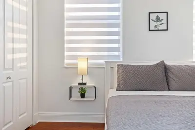 a bedroom with a bed and a table with a lamp at Luxury 5BR Villa Private Pool I Jacuzzi I BBQ I Piano I Near Miami Airport in Kendale Lakes