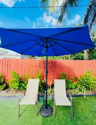 two chairs and a blue umbrella in the grass at Modern Boho 3BR Duplex Escape with Pool & King Bed Near Beach in Fort Lauderdale