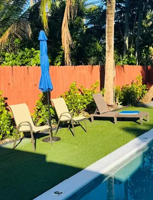 two chairs and a blue umbrella next to a swimming pool at Modern Boho 3BR Duplex Escape with Pool & King Bed Near Beach in Fort Lauderdale
