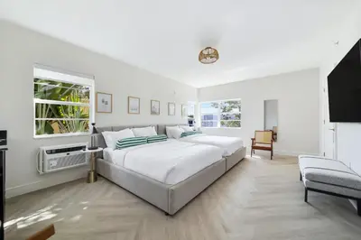 a white bedroom with a large bed and a tv at The Lemon Branch Hotel in Miami Beach
