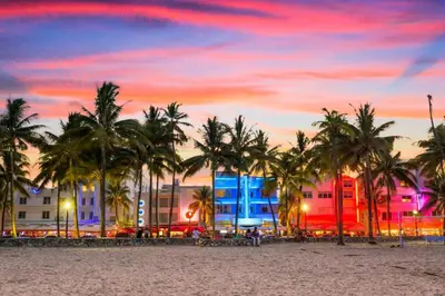 a beach with palm trees and buildings at sunset at Ocean Front Studio - Miami Beach in Miami Beach