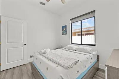 a white bedroom with a bed and a window at Oasis Yard -Pool-Jets-Game Room-BBQ-Relaxing in Carver Ranches