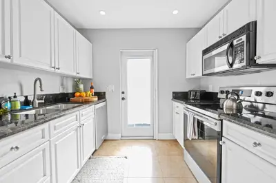 a white kitchen with white cabinets and a sink at 2 bed, steps from Wilton Drive, BBQ, fire pit in Fort Lauderdale