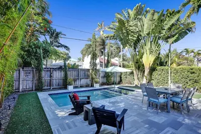 a backyard with a pool with chairs and a table at Fun Location! 1 block to Las Olas Pool & Parking in Fort Lauderdale