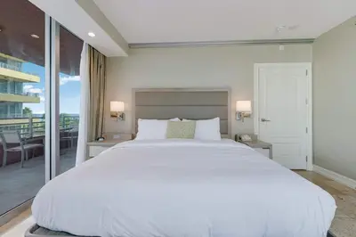a bedroom with a large white bed and a balcony at Oceanfront Retreat- South Beach Pool Amenities in Miami Beach