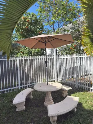 a picnic table with an umbrella and two benches at Cozy 1BR Beach Apartment Walk to Miami Beach in Miami Beach