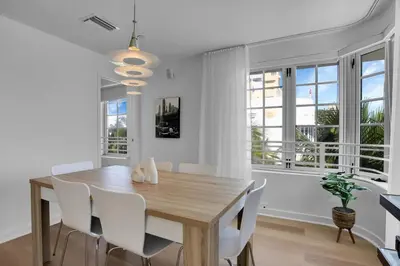 a dining room with a wooden table and white chairs at Peaceful 2BR Condo with Ocean Views on Ocean Drive South Beach in Miami Beach