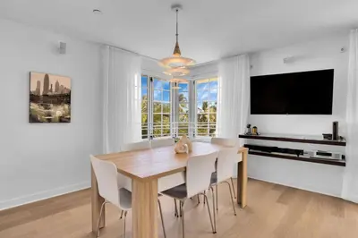 a dining room with a table and chairs and a tv at Peaceful 2BR Condo with Ocean Views on Ocean Drive South Beach in Miami Beach