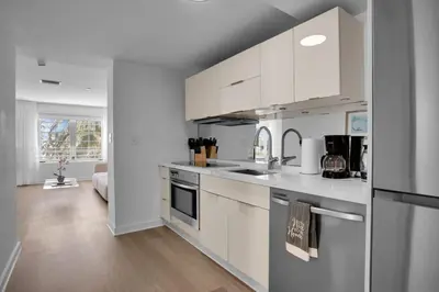 a kitchen with white cabinets and a living room at Peaceful 2BR Condo with Ocean Views on Ocean Drive South Beach in Miami Beach