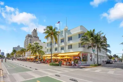 a large white building with palm trees and a street at Peaceful 2BR Condo with Ocean Views on Ocean Drive South Beach in Miami Beach