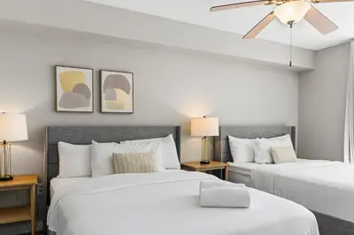 two beds in a bedroom with white walls and a ceiling fan at Stylish Brickell Stay with Ocean Views & Pool in Miami
