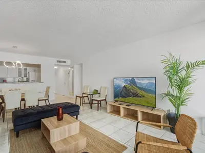 a living room with a blue couch and a kitchen at Sea Air Towers - Oceanfront Condo w Pool & Gym in Hollywood