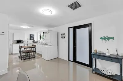 a kitchen with white cabinets and a table and a door at Buena Vista vacation home with privacy and close to everything in Miami