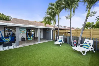 a backyard with two lawn chairs and palm trees at Serene Lakefront Getaway Fishing & Kayaks in Fort Lauderdale