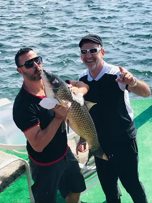 two men standing on a boat holding a fish at Serene Lakefront Getaway Fishing & Kayaks in Fort Lauderdale