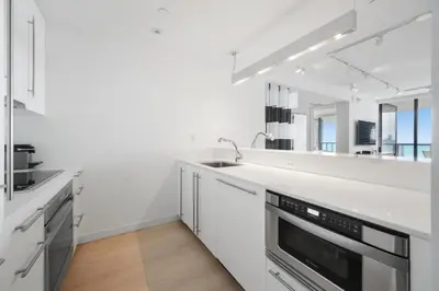 a white kitchen with a sink and a mirror at OceanView 1B Private Residence at South Beach -1614 in Miami Beach