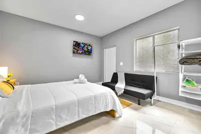 a bedroom with a white bed and a chair at Modern Studio in Wynwood Midtown in Miami