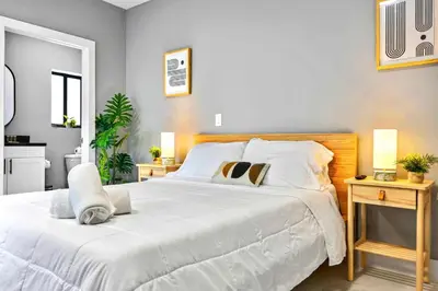 a bedroom with a large white bed with two tables at Modern Studio in Wynwood Midtown in Miami