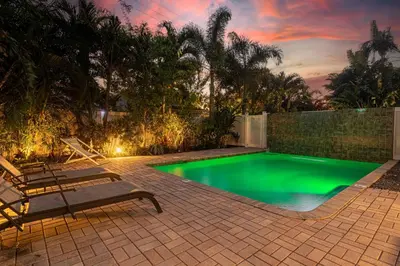 a swimming pool in a backyard with a bench at Wilton Manors Twin Oasis | 2 Heated Pools, For 12 in Fort Lauderdale